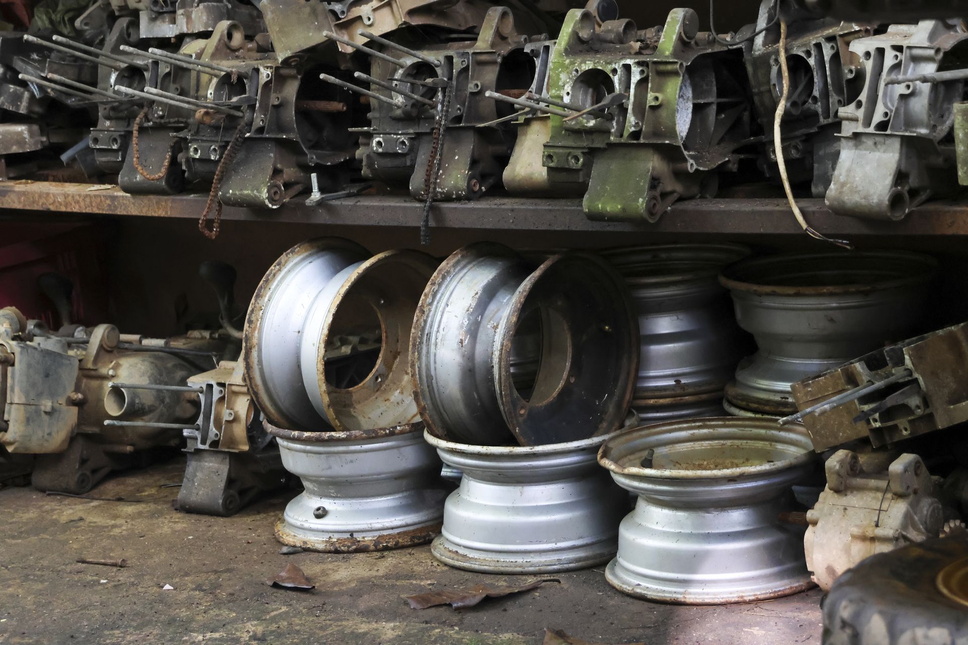 Metal wheel rims and engine components pile up in a cluttered garage.