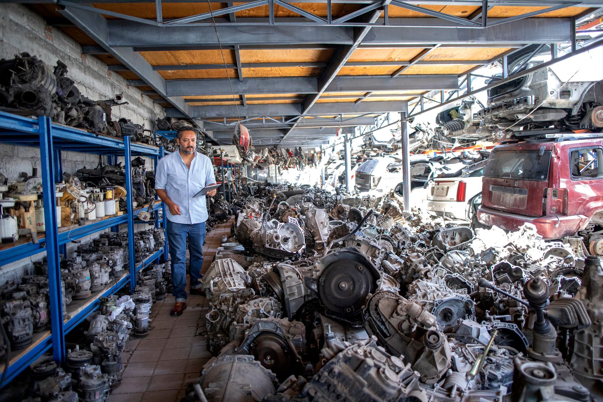 A man is checking the inventory of used auto parts.