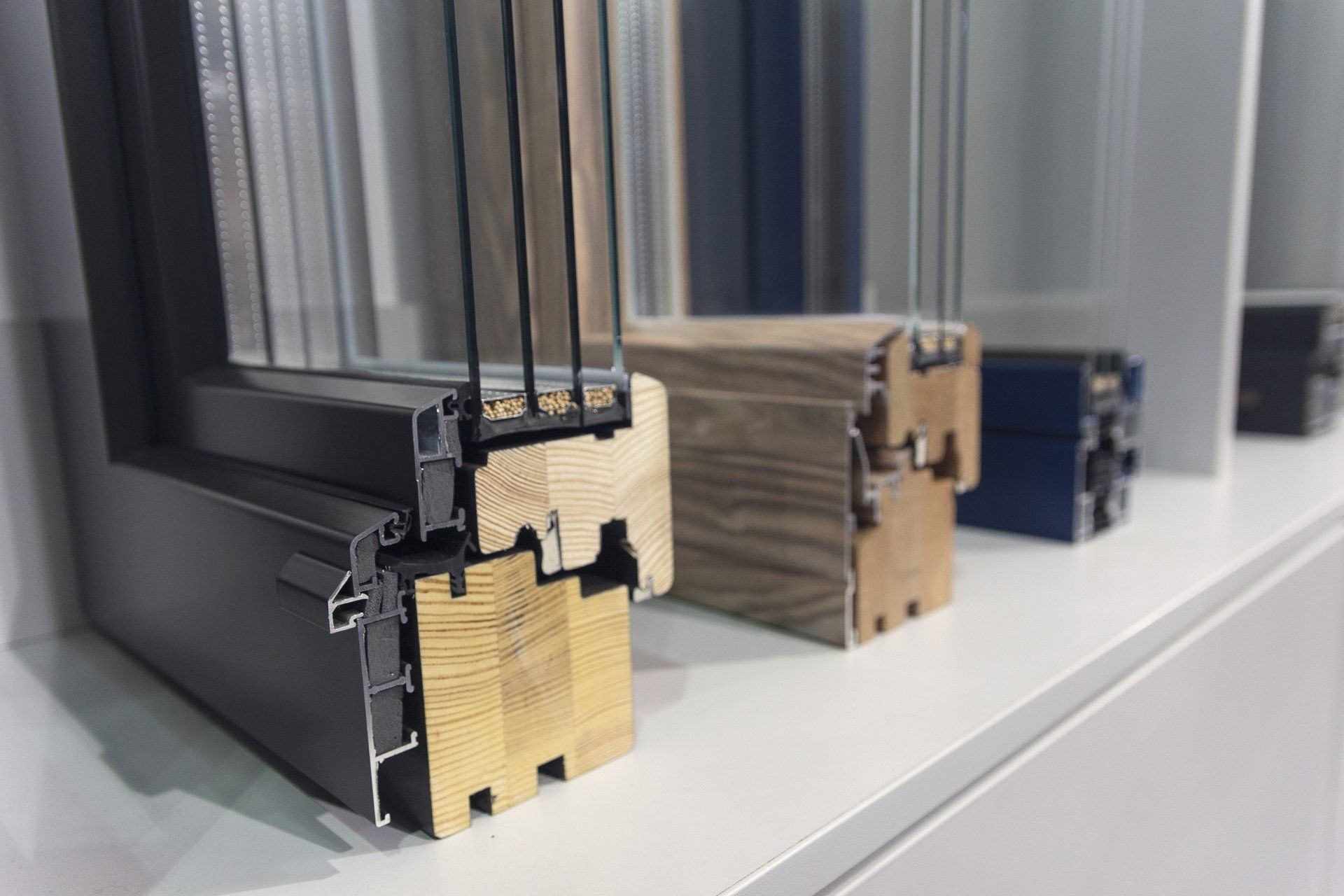 Campioni in sezione trasversale di telai per finestre in vari colori su uno scaffale.