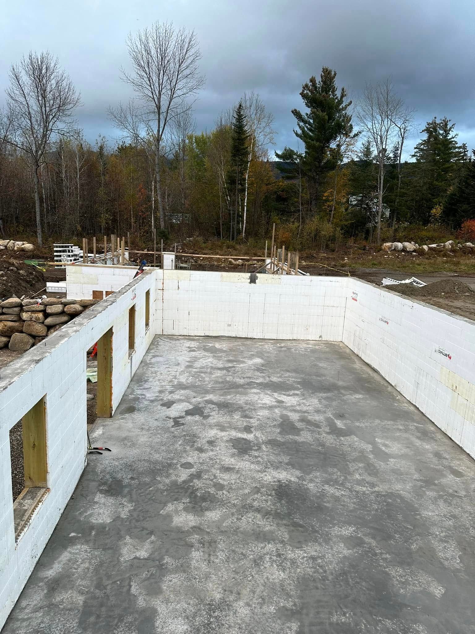 Concrete foundation slab with white retaining walls in a wooded outdoor area