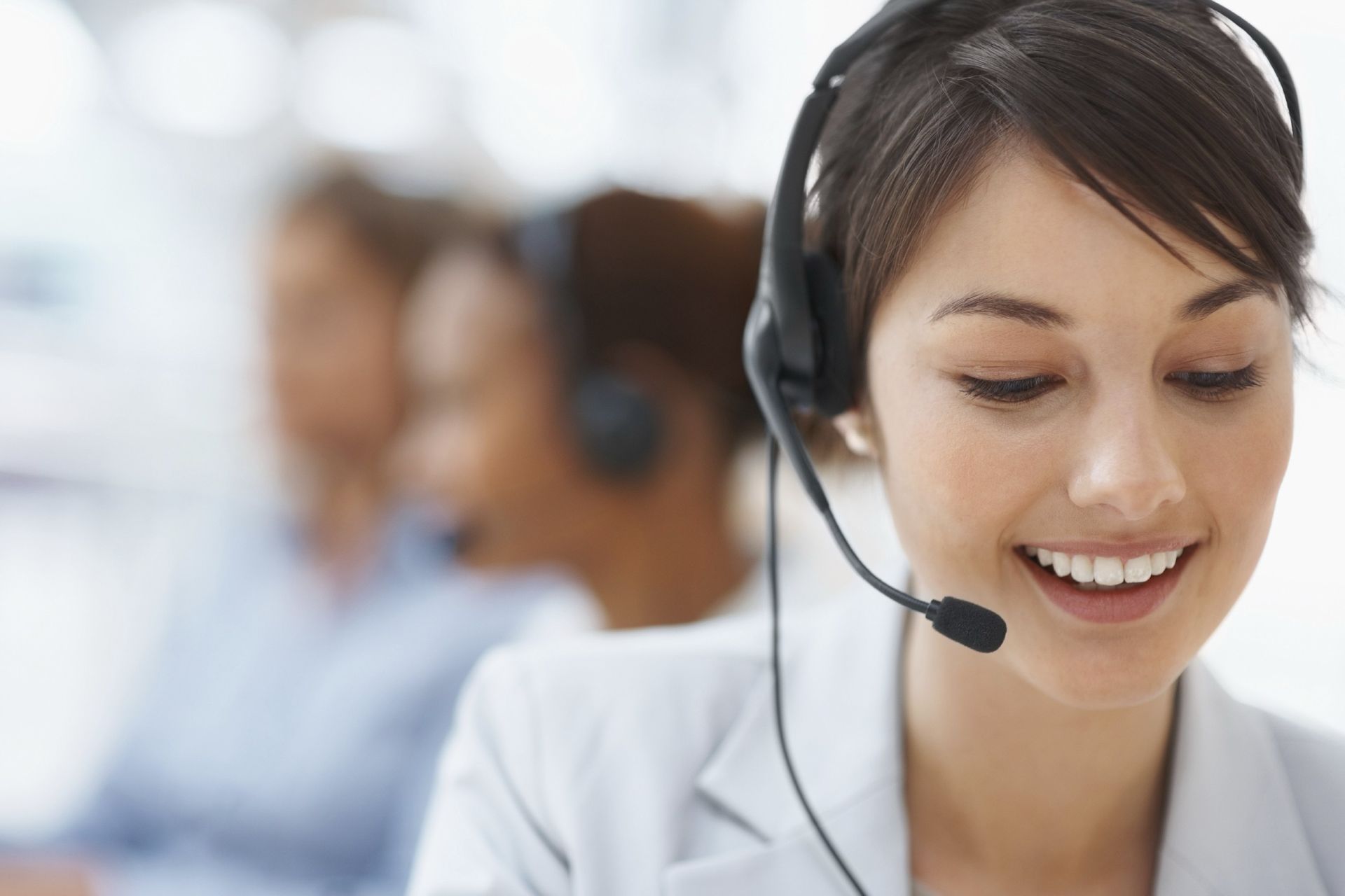 A woman wearing a headset is smiling in a call center