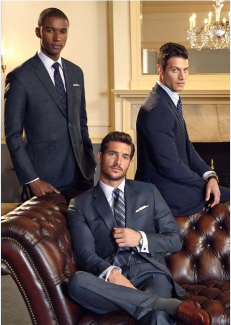 Three men in suits pose, one seated on a leather sofa. They wear ties, in an elegant interior setting. Three men in suits pose, one seated on a leather sofa. They wear ties, in an elegant interior setting.