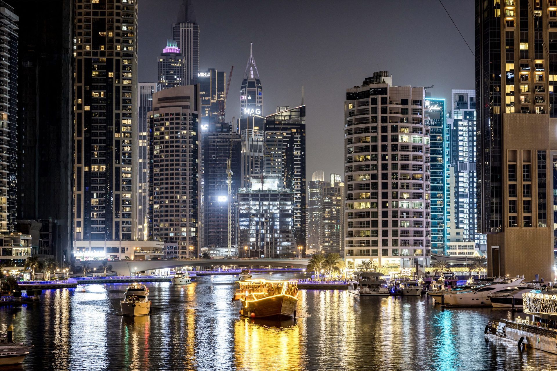 A boat is floating on a body of water in front of a city skyline at night.