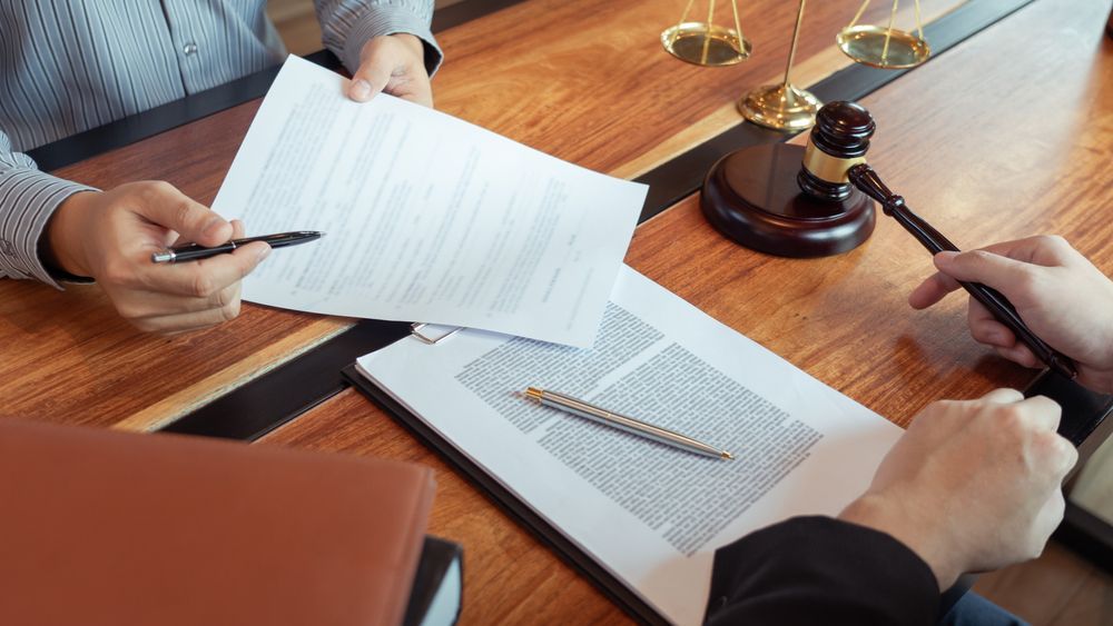Two People Reviewing Documents at a Table With a Gavel— Umbrella Legal in Lake Macquarie, NSW