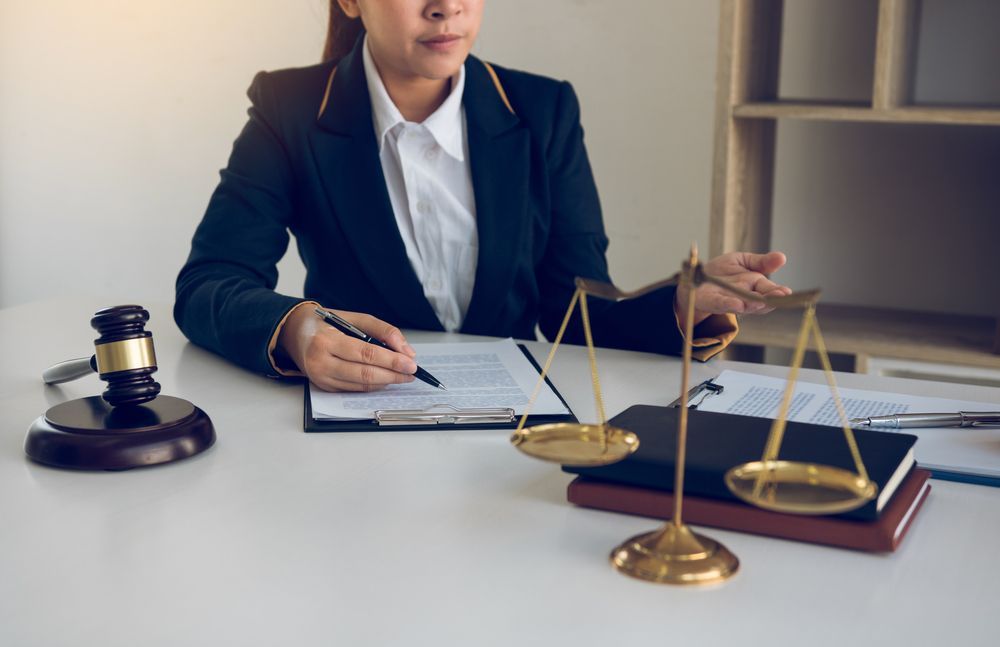 A Lawyer in a Suit Sits at a Desk With a Gavel and a Set of Scales — Umbrella Legal in Cardiff, NSW
