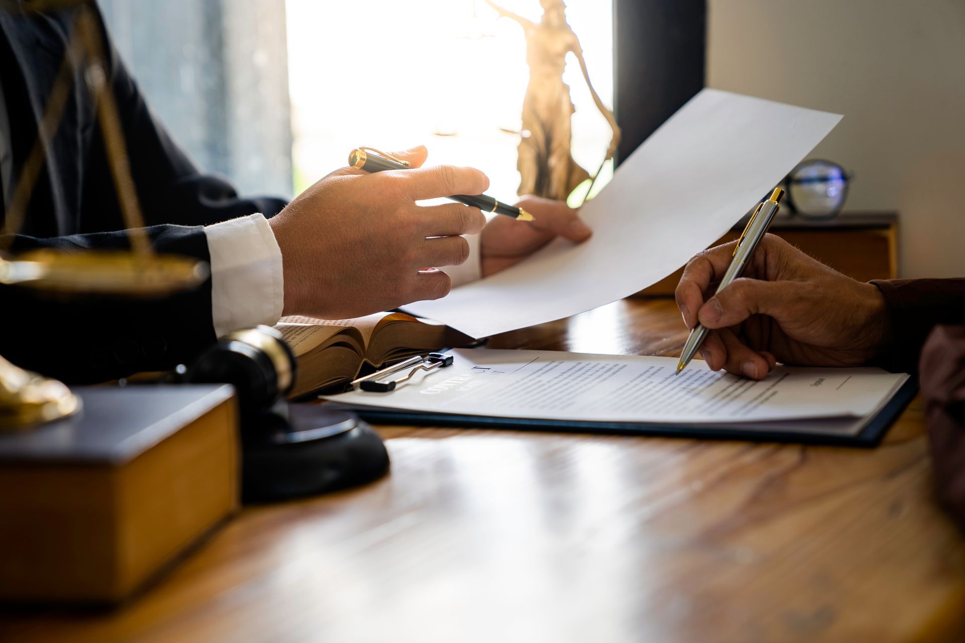 Two People at a Desk; One Signing a Document — Umbrella Legal in Cardiff, NSW