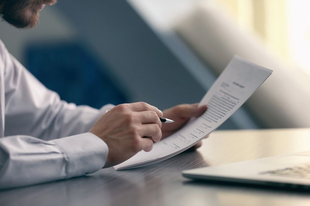 Person in White Shirt Reviewing Document With Pen — Umbrella Legal in Cardiff, NSW