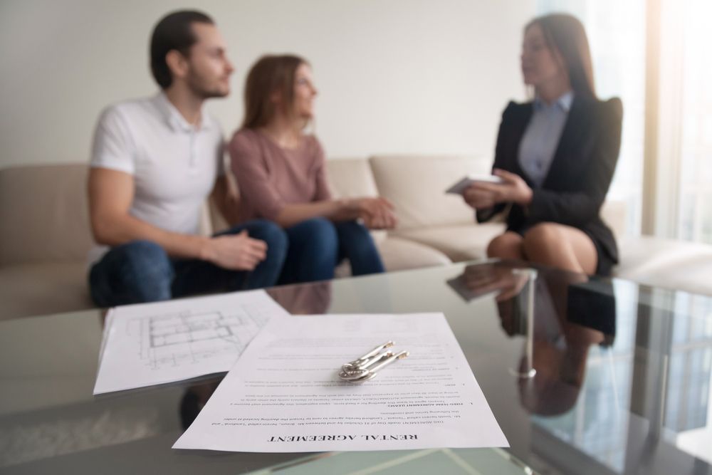 Couple on Couch, Reviewing Contract With Realtor — Umbrella Legal in Cardiff, NSW