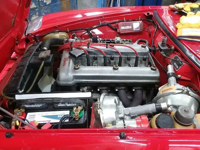 Cars being serviced in a mechanic's garage with cars on lifts, tools, and equipment visible.