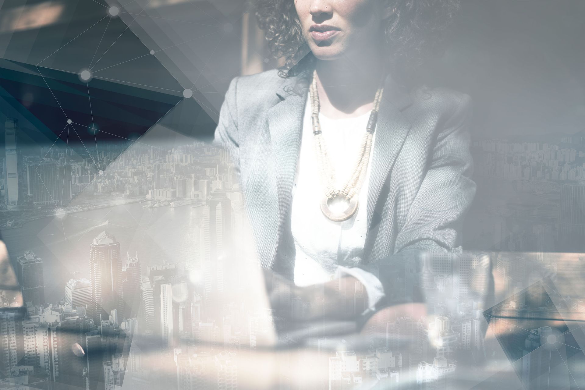 Stylish man in a gray suit at a table, with a laptop and city reflections in a bright, hazy room