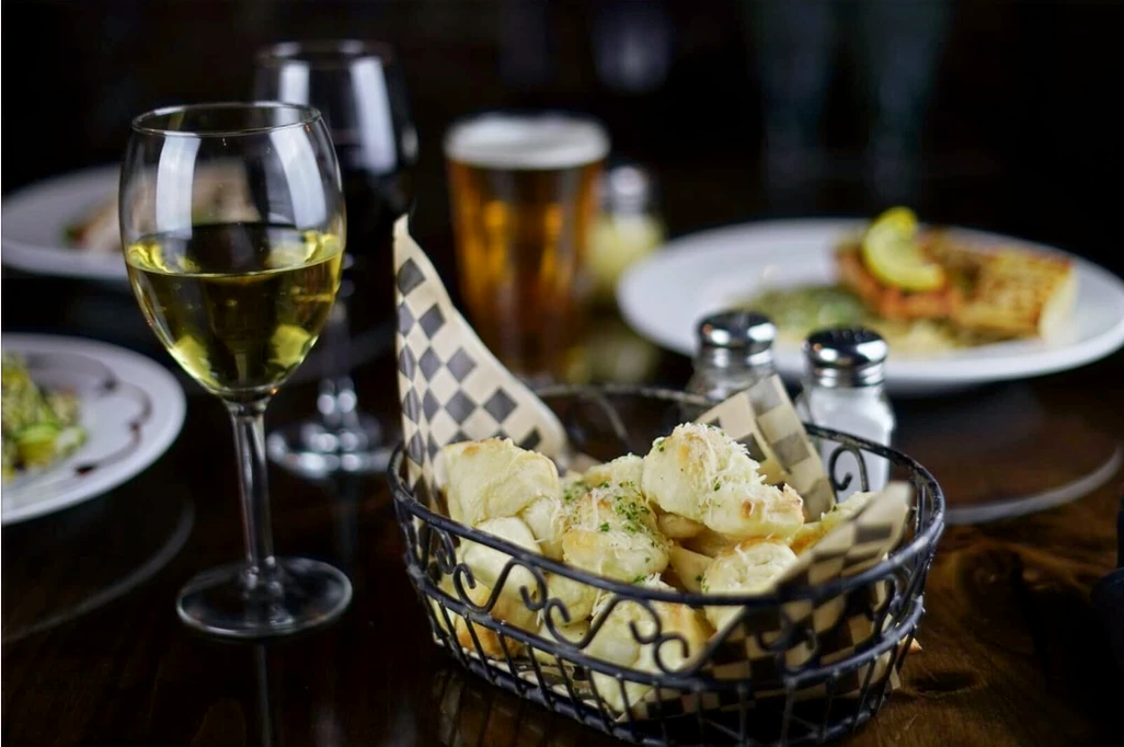 A basket of chips and a glass of wine on a table.