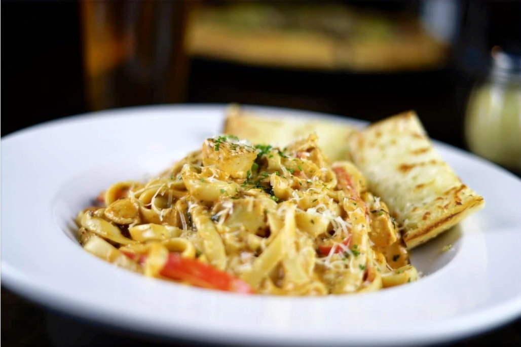 A white plate topped with pasta and garlic bread
