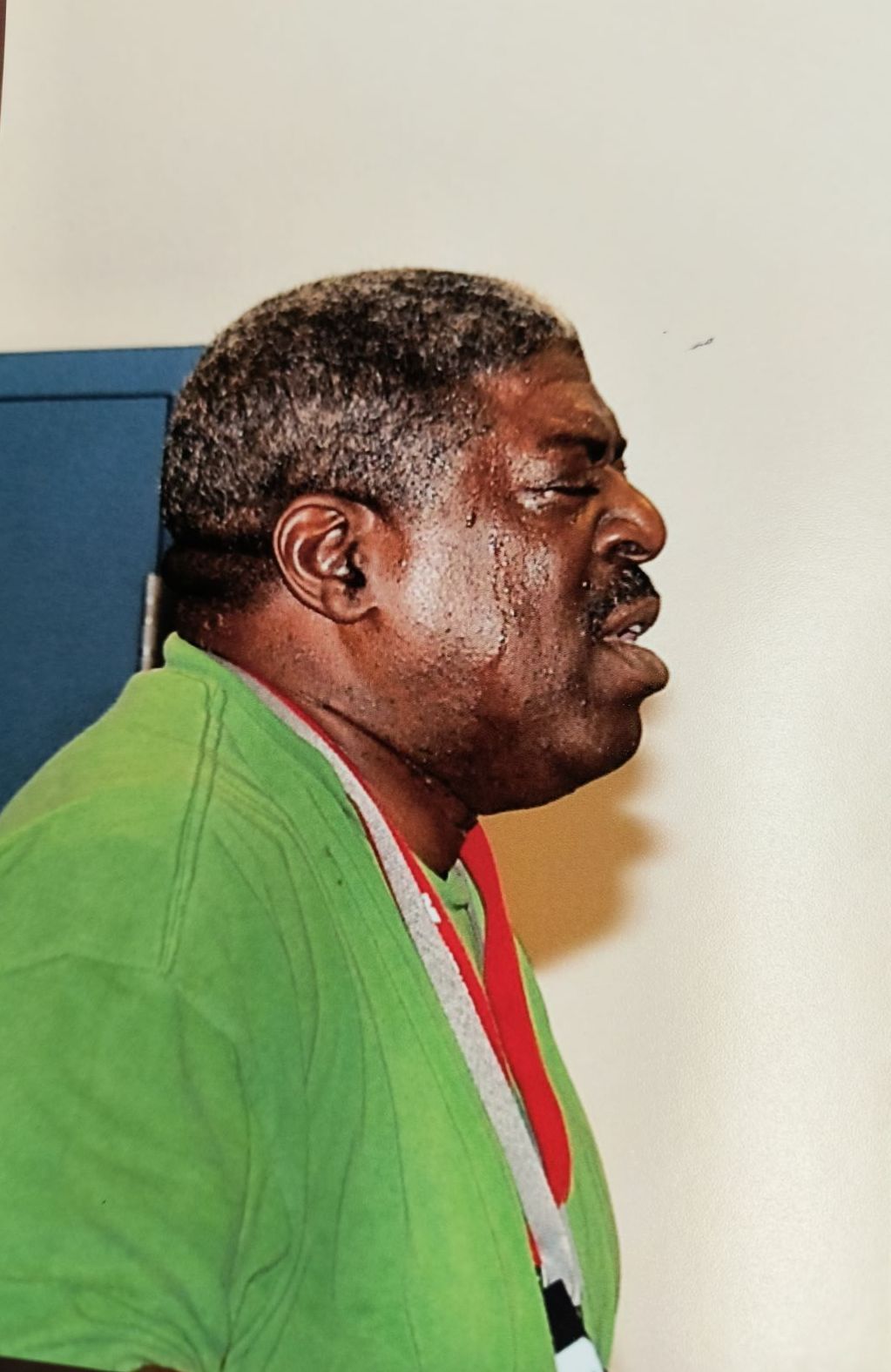 A man in a green shirt with a red lanyard around his neck