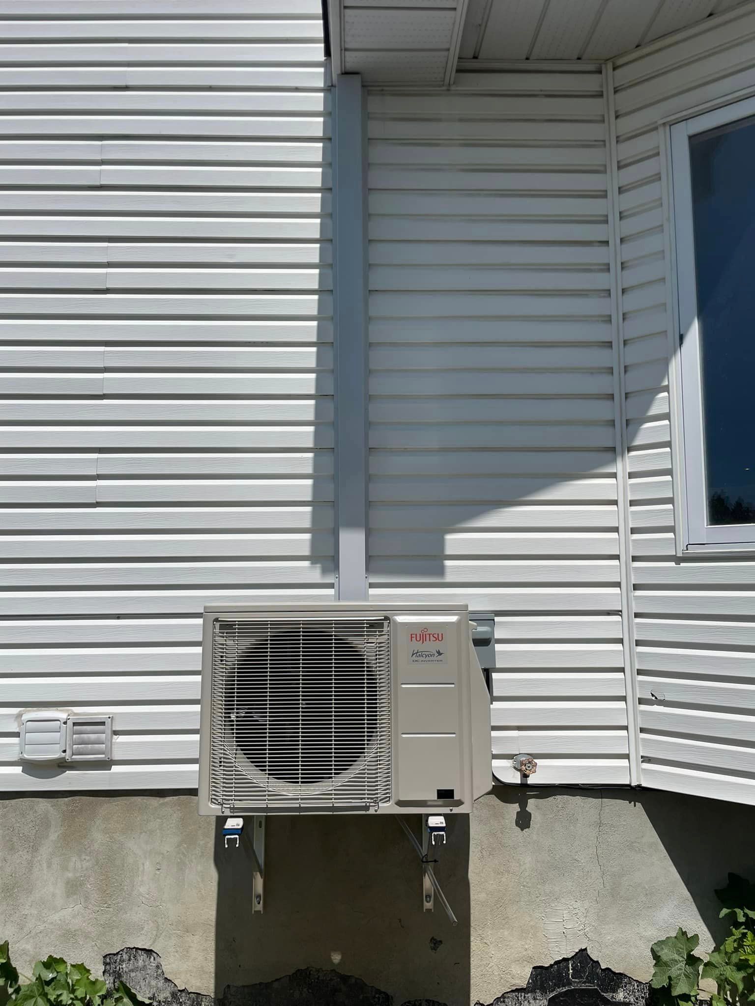 Une maison blanche avec un climatiseur cassé sur le côté