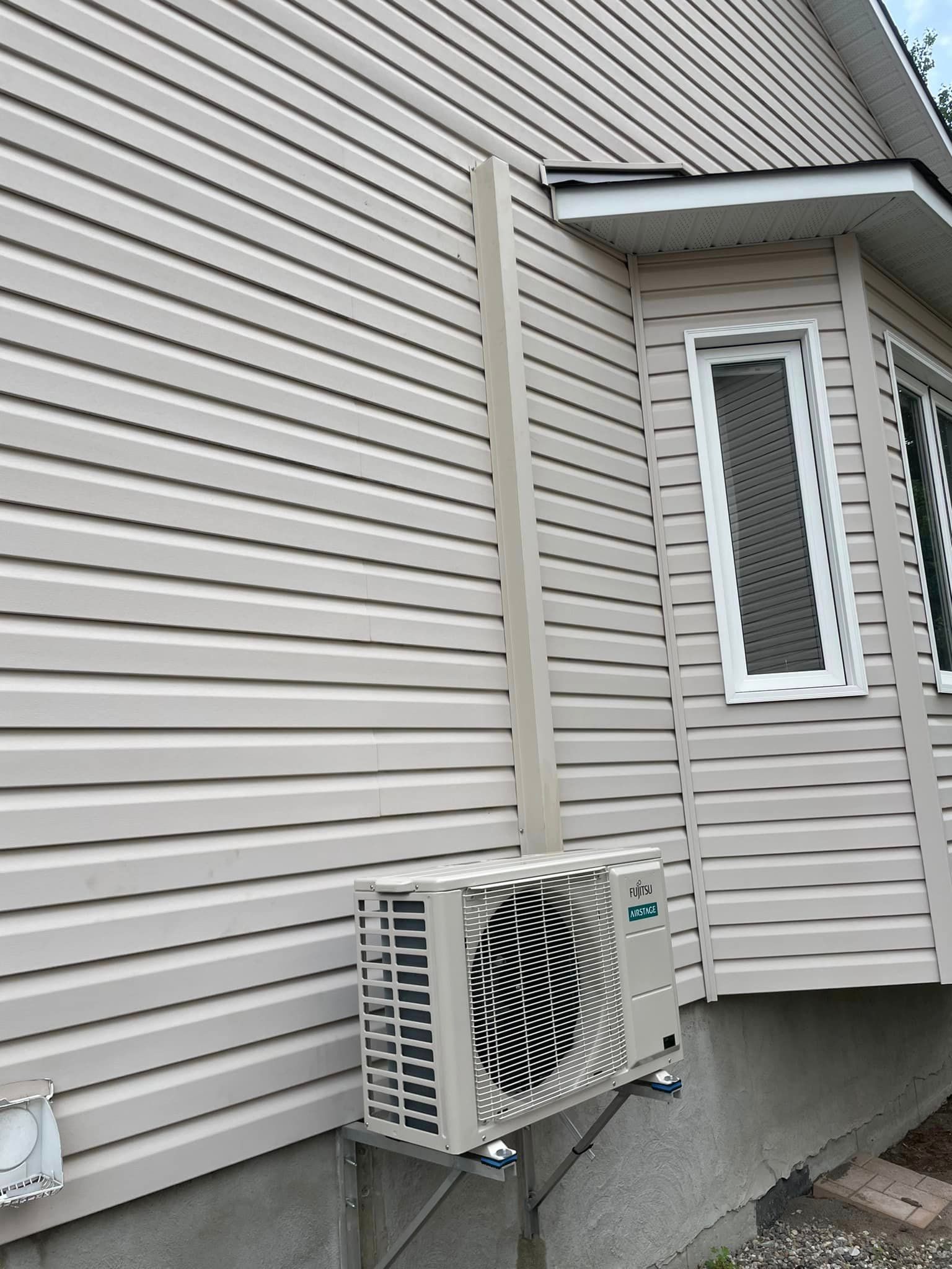Un climatiseur est installé sur le côté d'une maison.
