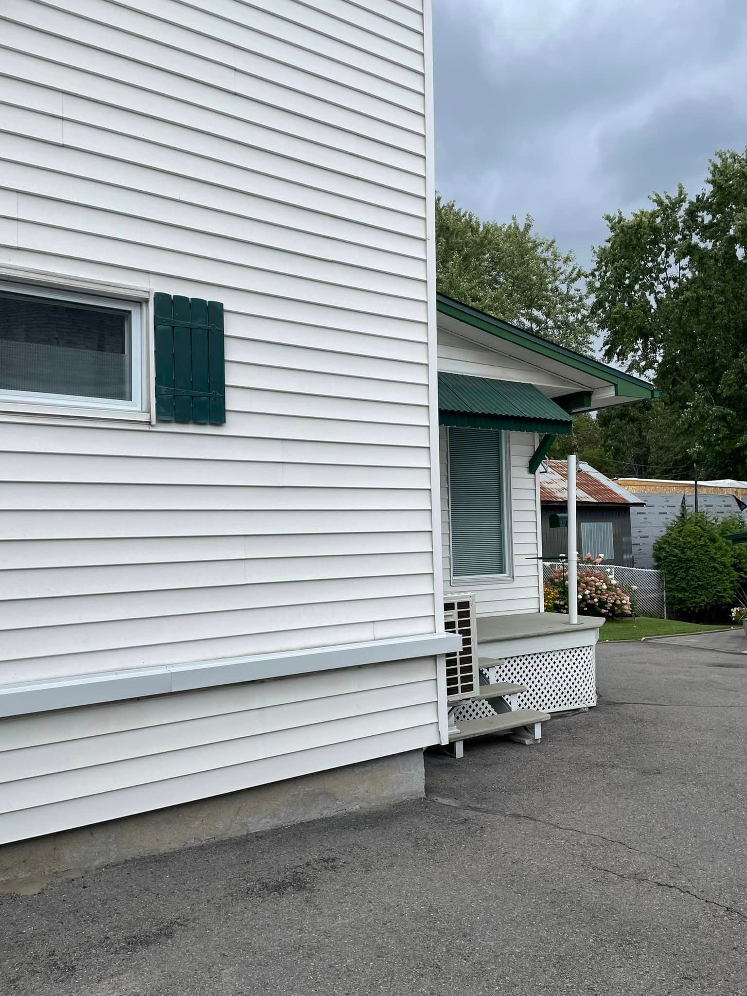 Une maison blanche avec un auvent vert sur le côté