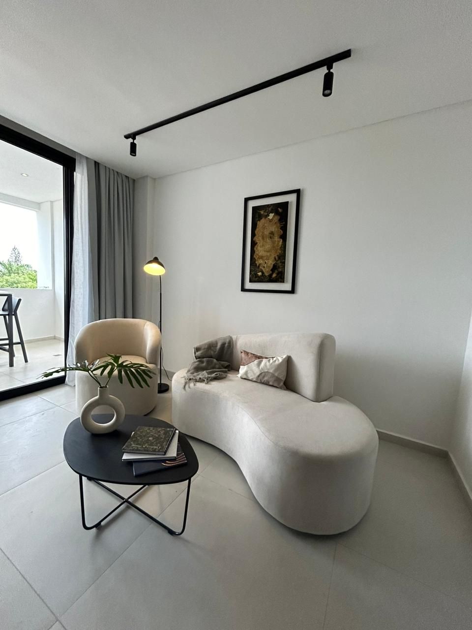Moderna sala de estar con sofá curvo de color crema, sillón, mesa de centro negra, obras de arte