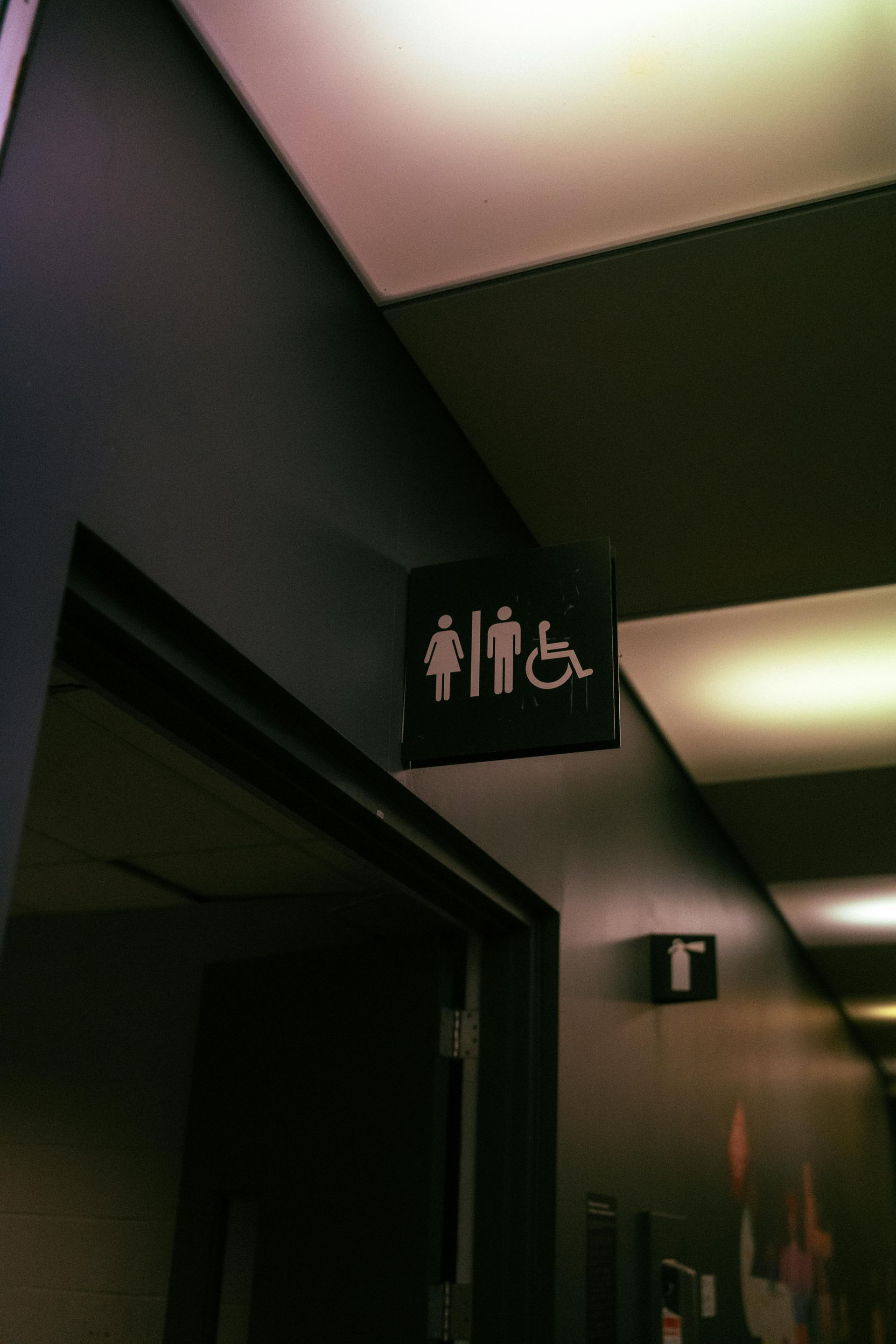 Un cartel que anuncia un baño para discapacitados cuelga del techo.