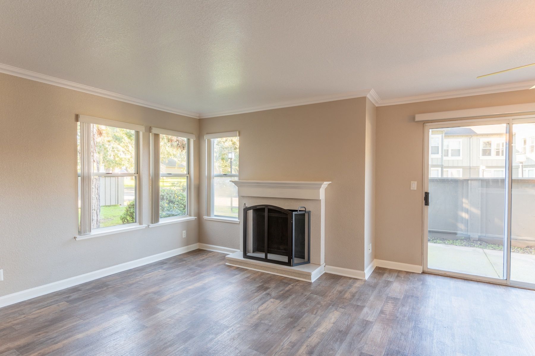 Bright living room with a fireplace, wood-look flooring, and a sliding glass door to a patio.