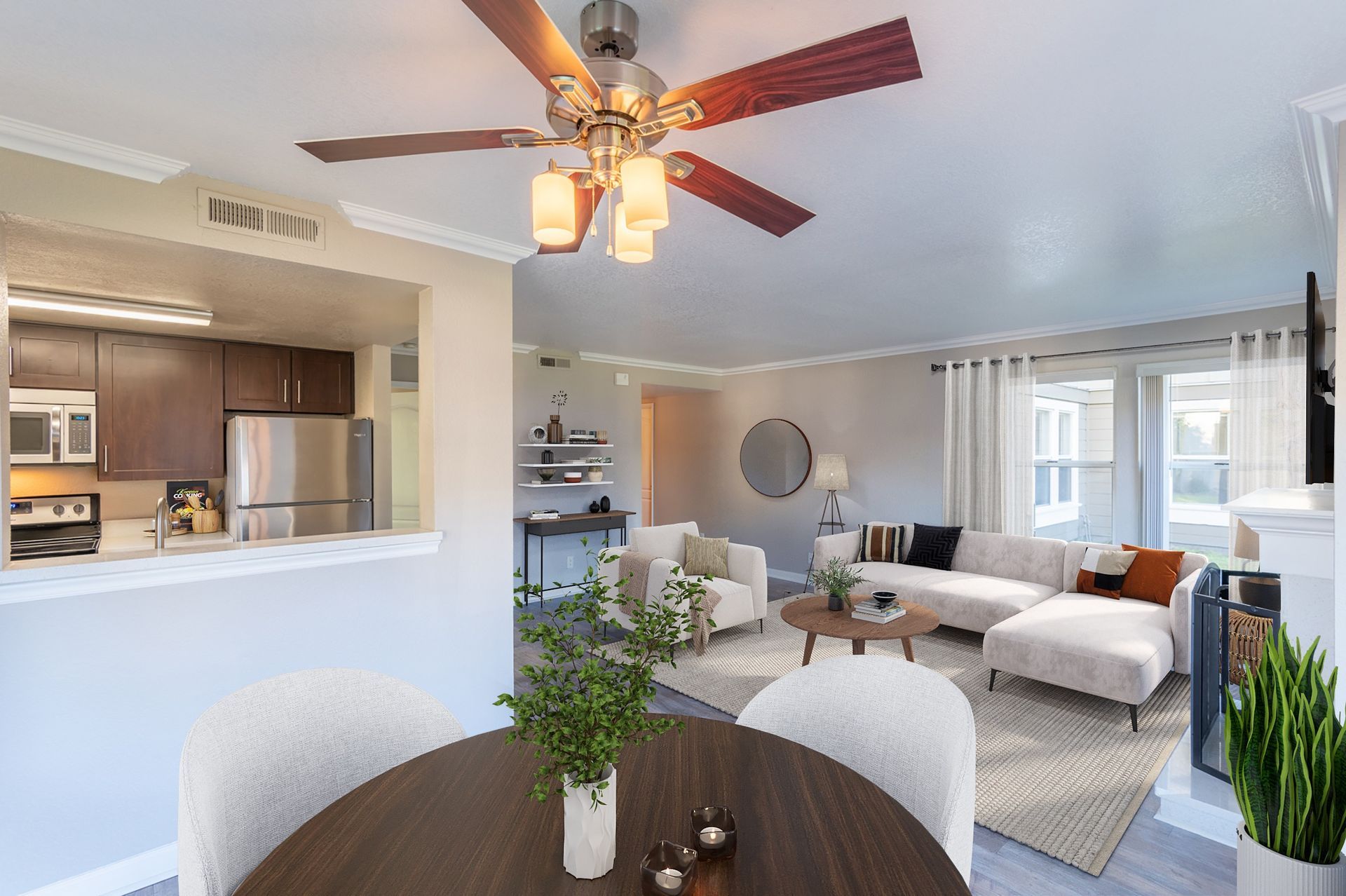 Open-concept apartment living area with kitchen pass-through, dining table, and beige sofa.