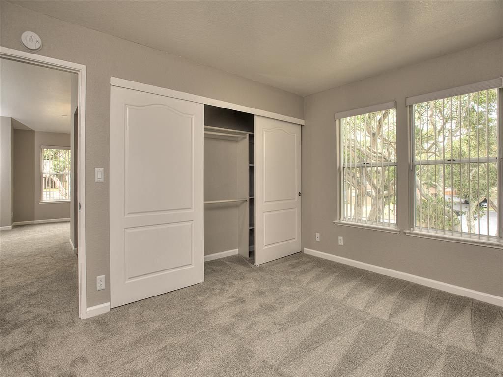 Bedroom with carpet, sliding closet doors, and two windows