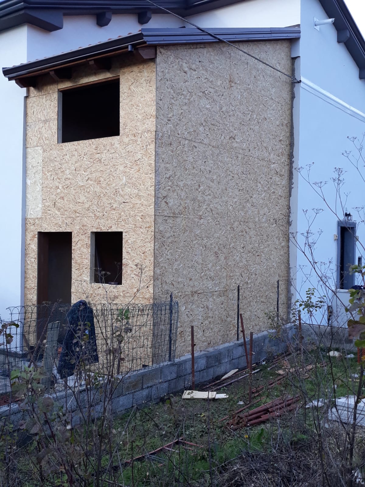 Una casa in fase di ristrutturazione con una recinzione davanti