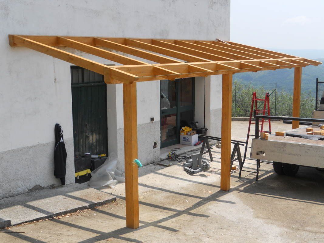 Un pergolato in legno viene costruito davanti a un edificio bianco