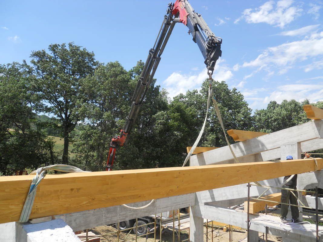 Una gru sta sollevando una trave di legno in un cantiere edile