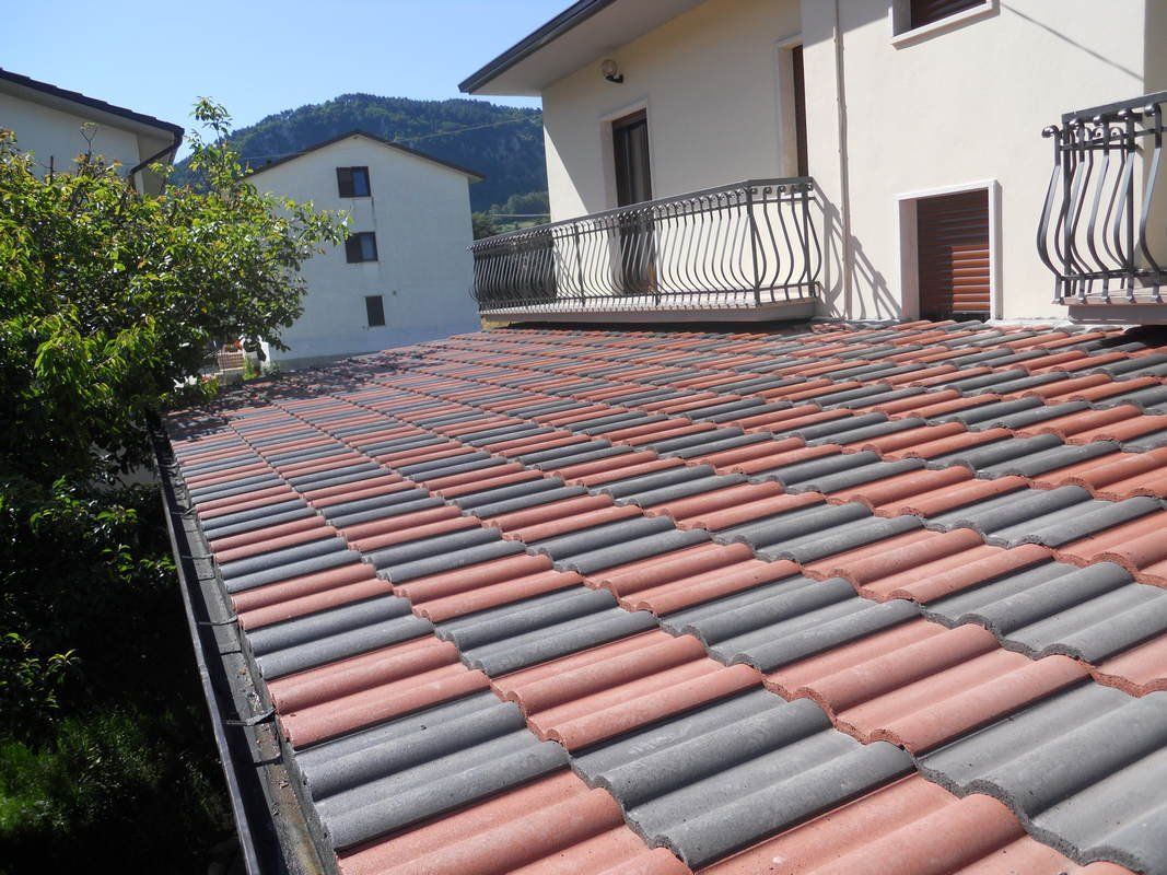Un tetto di tegole rosse e grigie con un balcone sullo sfondo