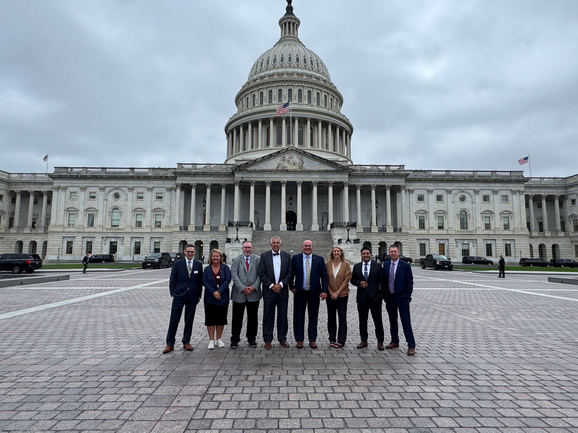 T4 Insurance team posing in front of the U.S. Capitol Building on a cloudy day.