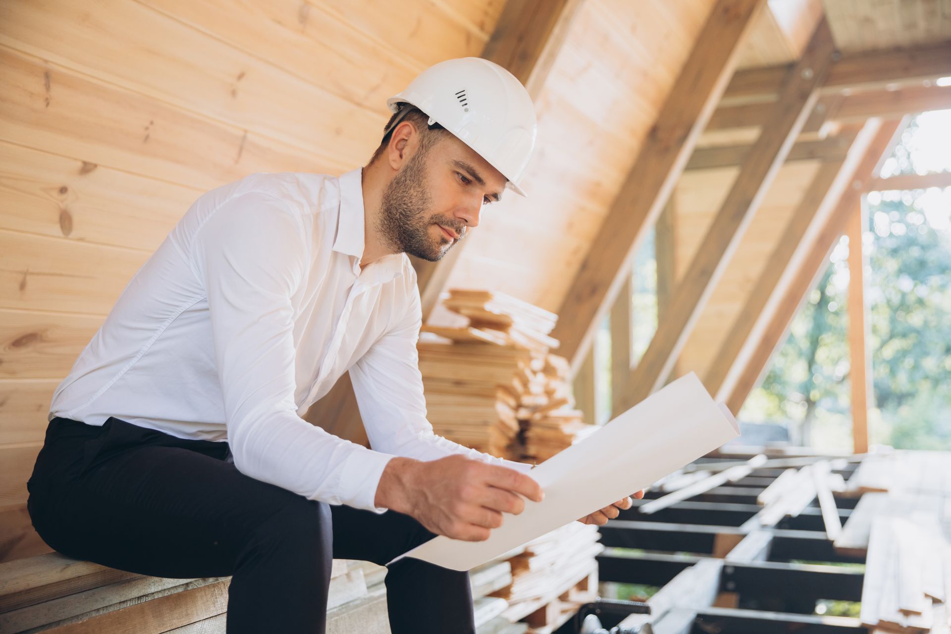 Man in hard hat reviews blueprints at a construction site.