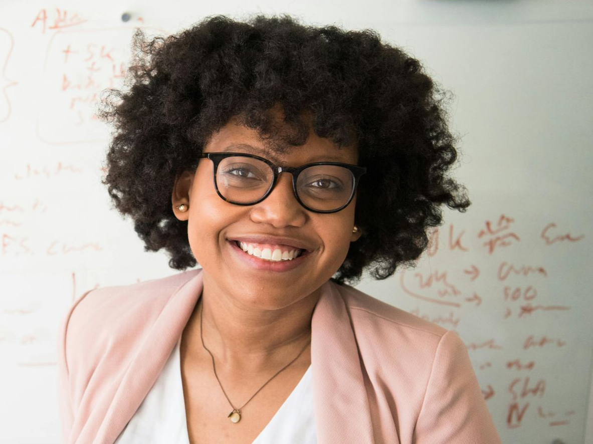 A woman in a blue jacket and white shirt is smiling