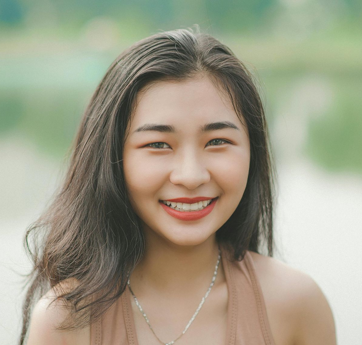 A woman in a black jacket and white ruffled blouse smiles for the camera