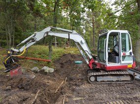 Septic tank being installed in the forest. Caterpillar with dipper digging