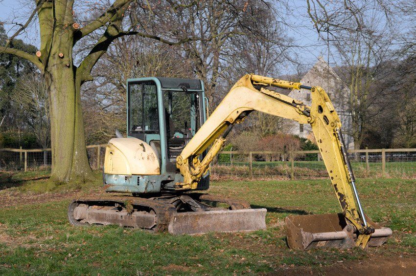 Digger in countryside digging holes in the ground
