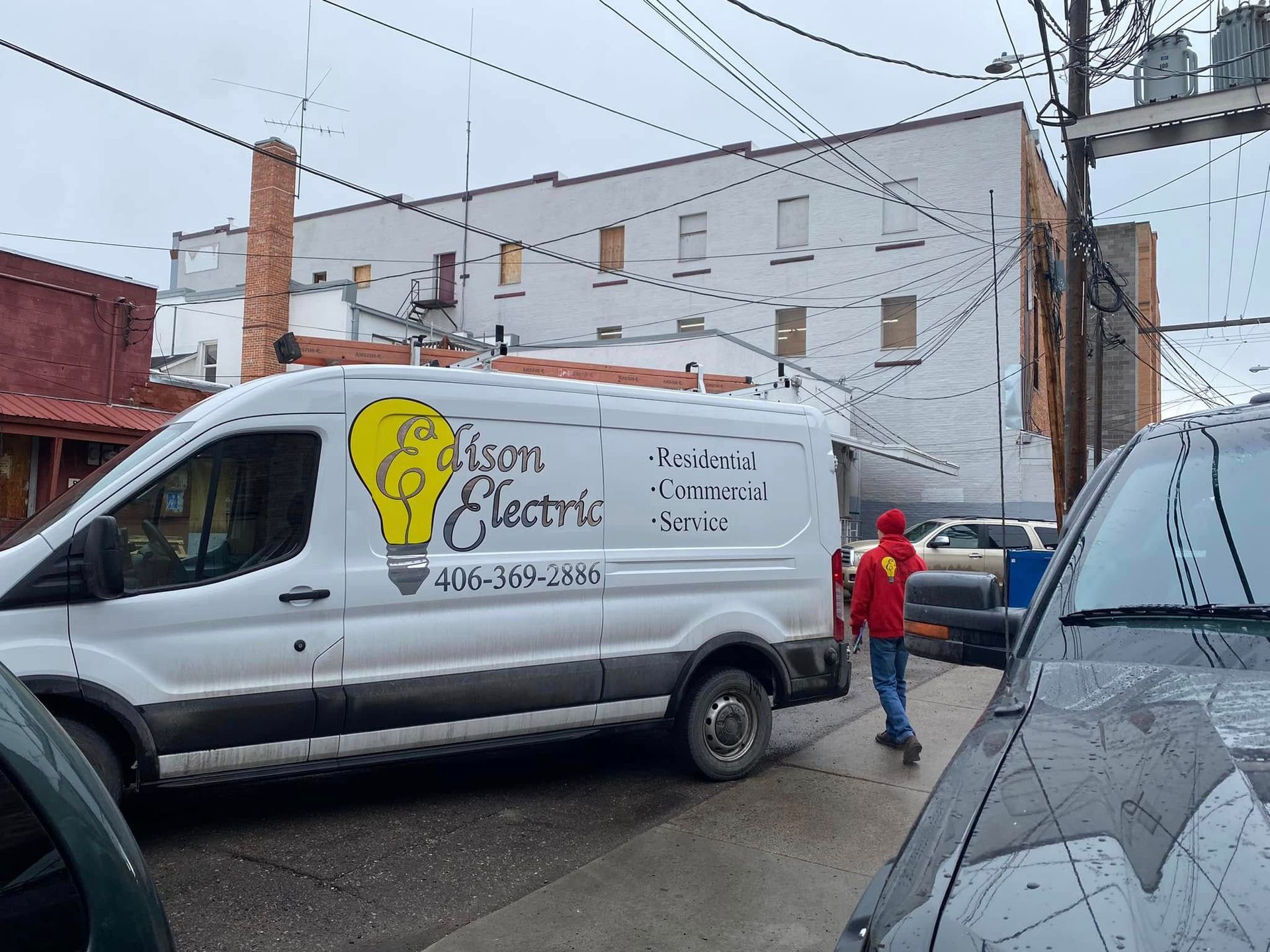 An open wall-mounted electrical distribution box with multiple circuit breakers and a tangle of exposed internal wiring.