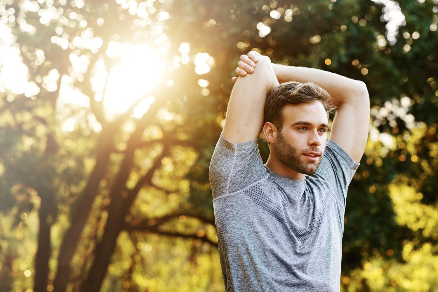 Man stretching arm outdoors in park.