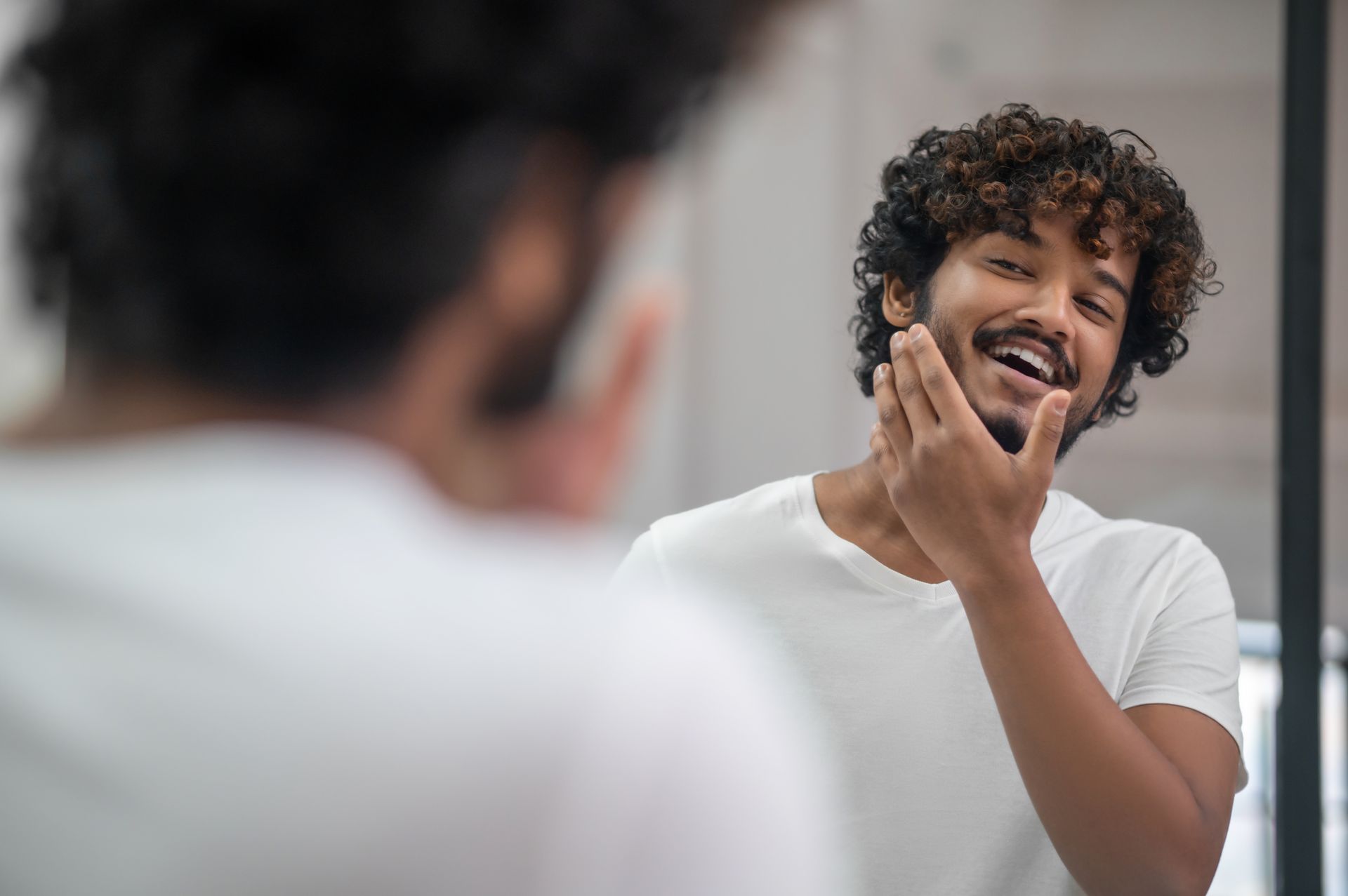 a man is looking at himself in the mirror and smiling .