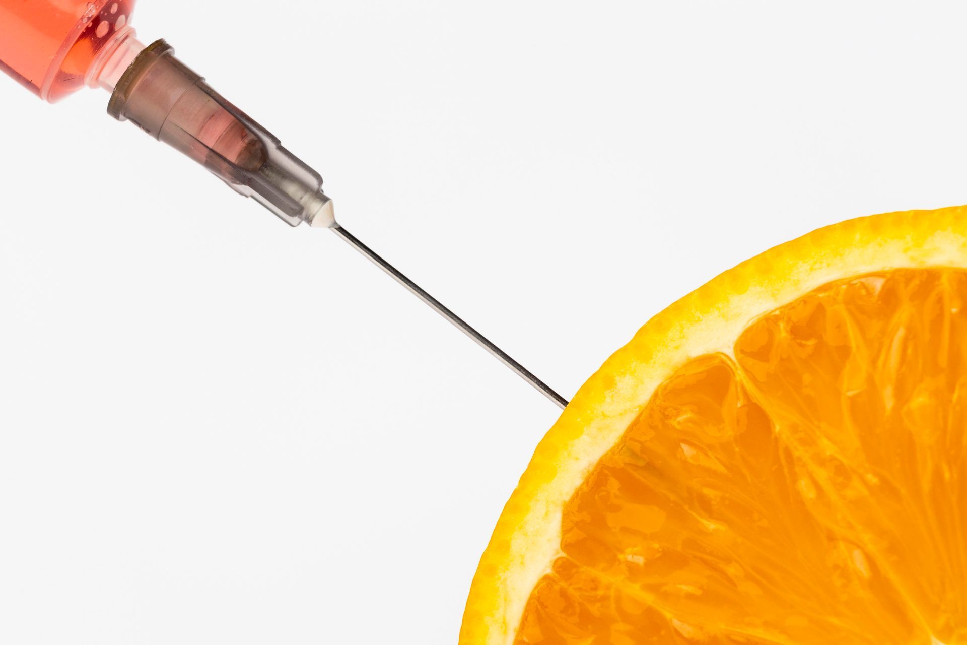 A syringe is being inserted into an orange slice.