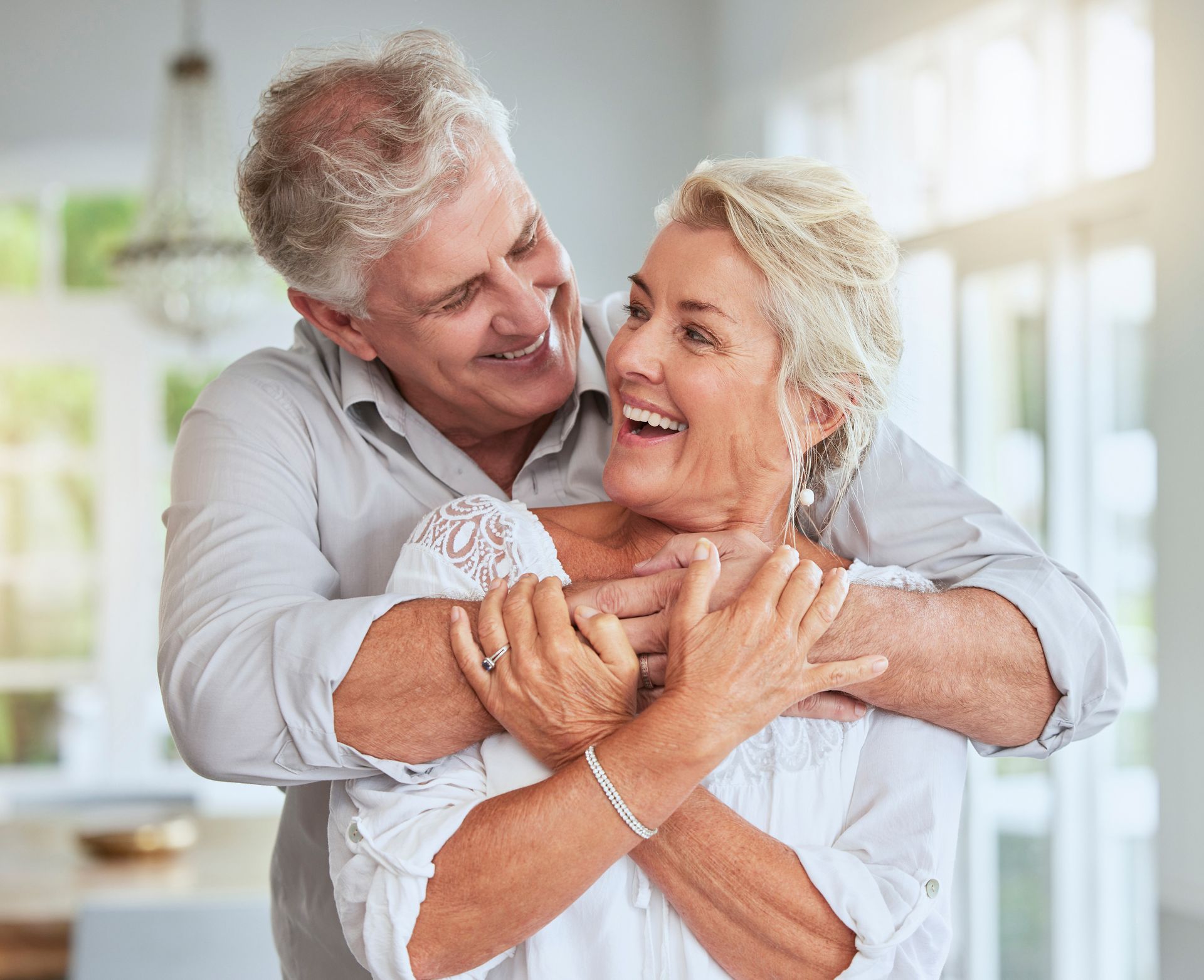 an elderly couple is hugging each other in a living room .