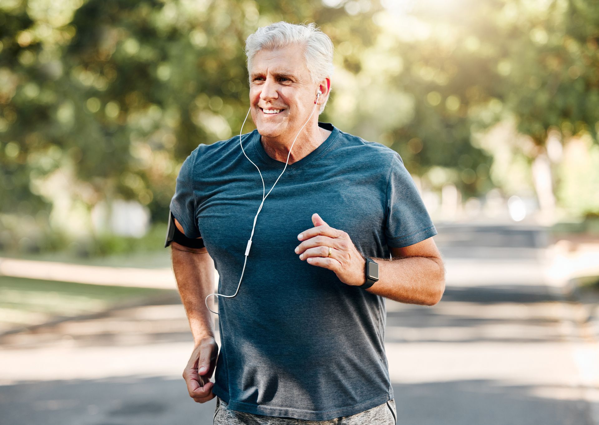 an older man is running in a park with headphones on .