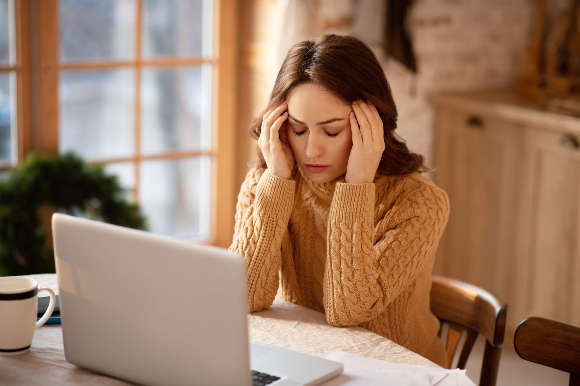 A woman is sitting at a table using a laptop computer.