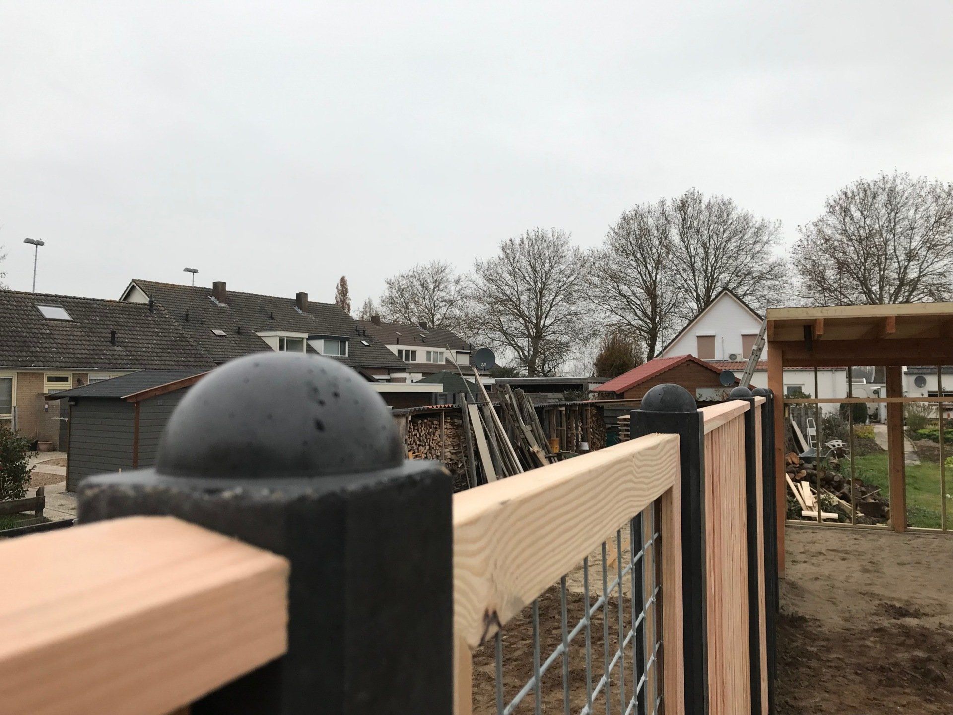 Een houten hek met daarop een zwarte bal