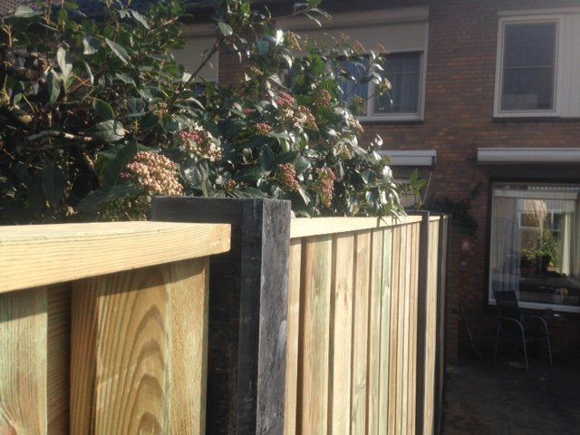 Een houten hek staat voor een bakstenen gebouw.