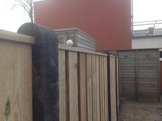 Een houten hek voor een rood gebouw