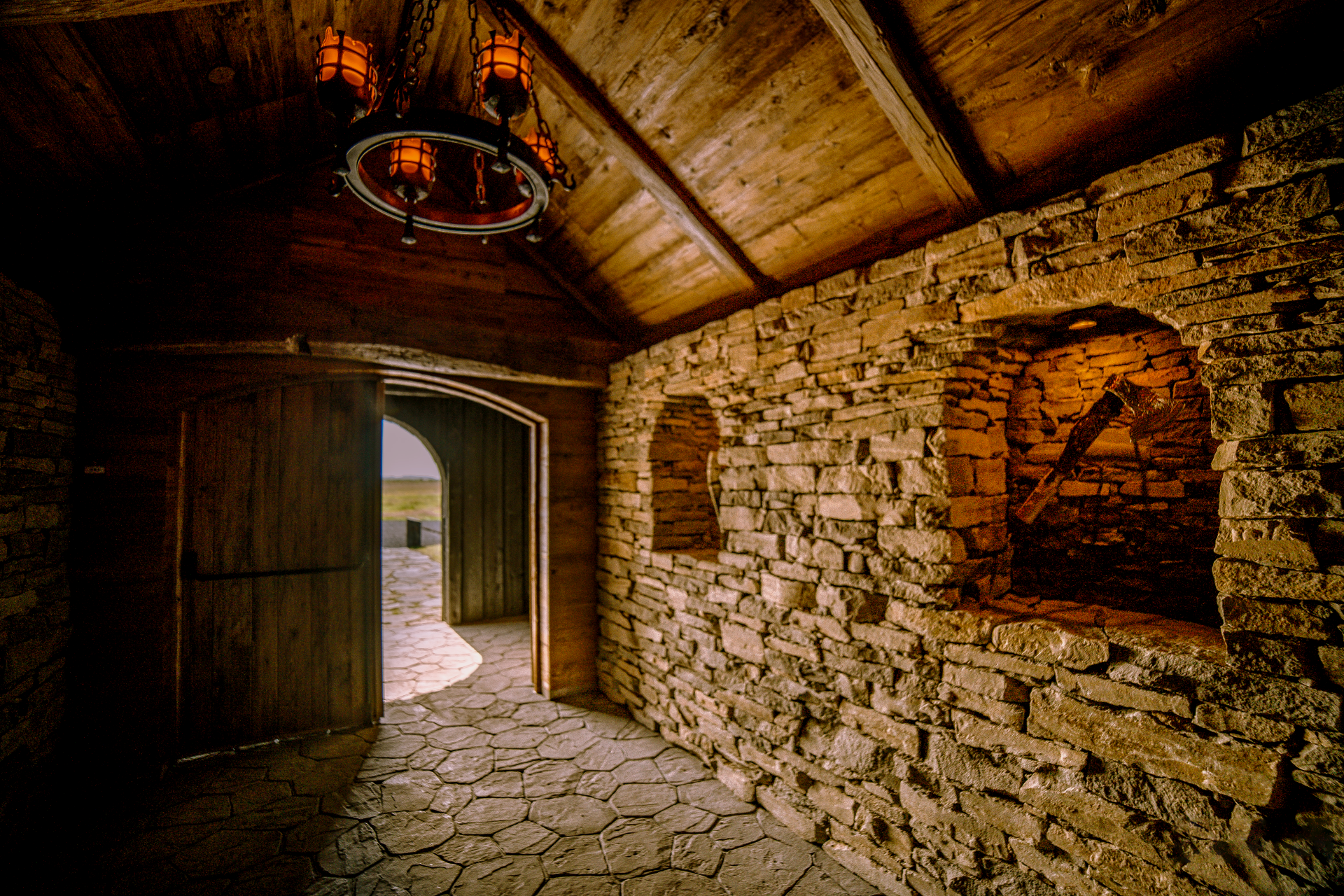 A stone wall with a wooden door and a chandelier hanging from the ceiling
