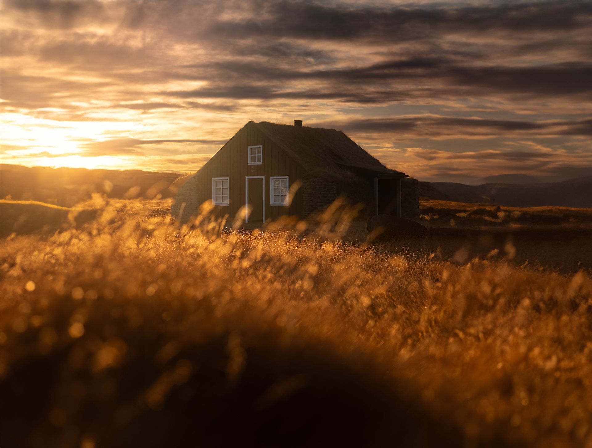 A house in the middle of a field at sunset.