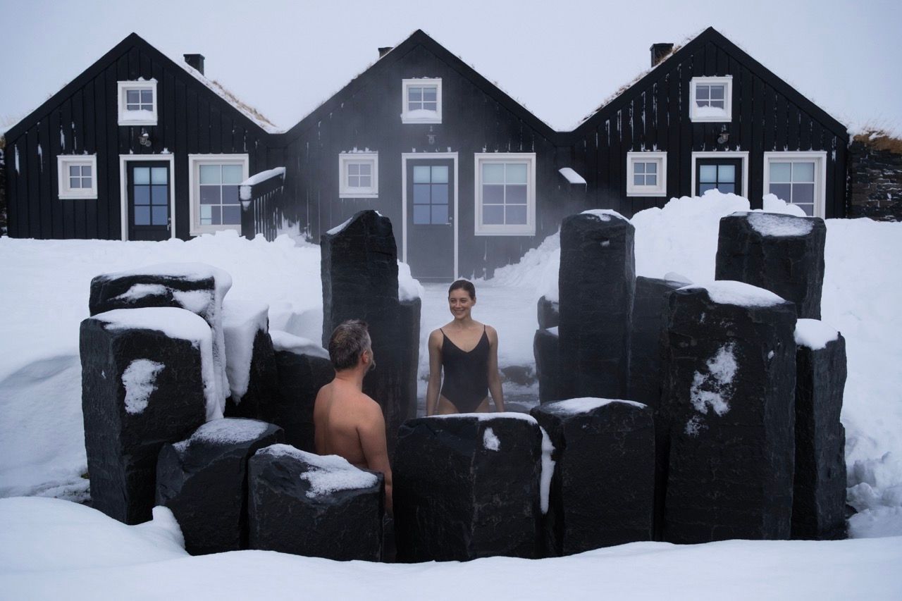 A man and a woman are in a hot tub in the snow