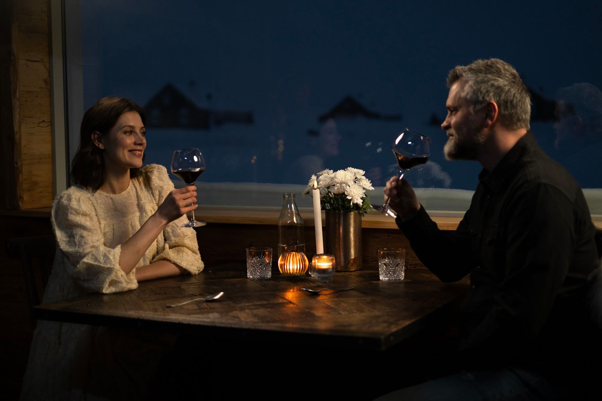 A man and a woman are sitting at a table drinking wine.