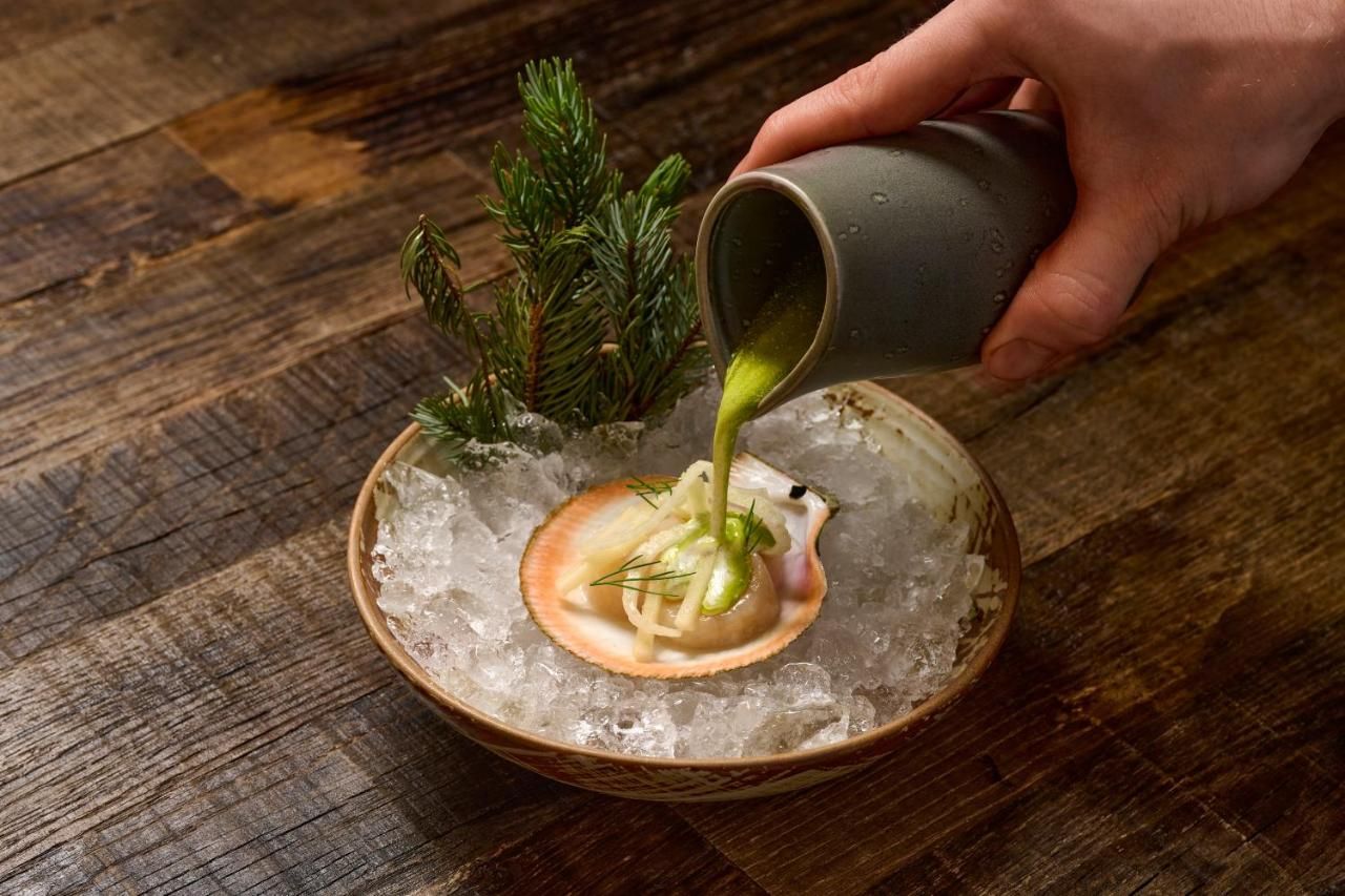 A person is pouring sauce on a plate of food on ice.